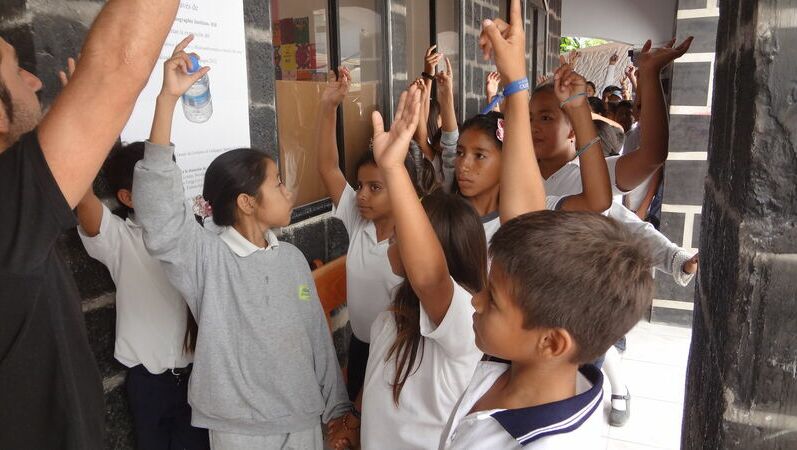 Eine Gruppe Schulkinder mit erhobenen Armen, während sie über den Naturschutz lernen.