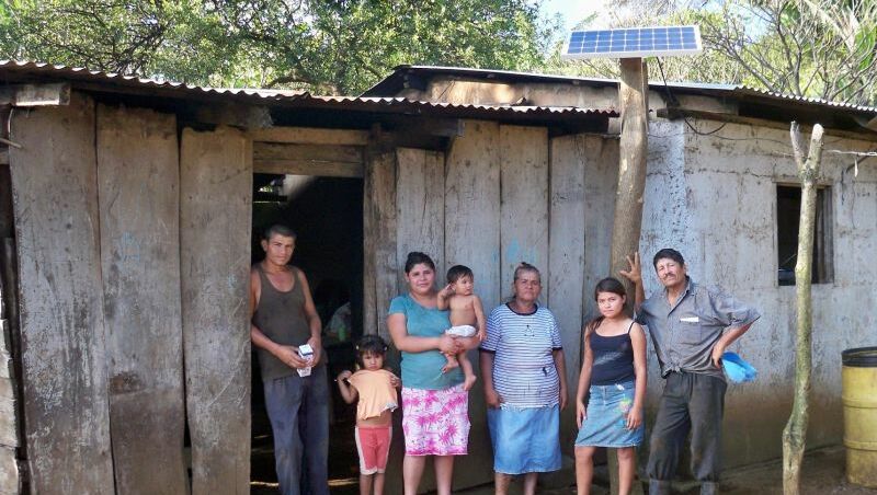 Eine siebenköpfige Familie steht vor einem Haus mit Solar Panel.