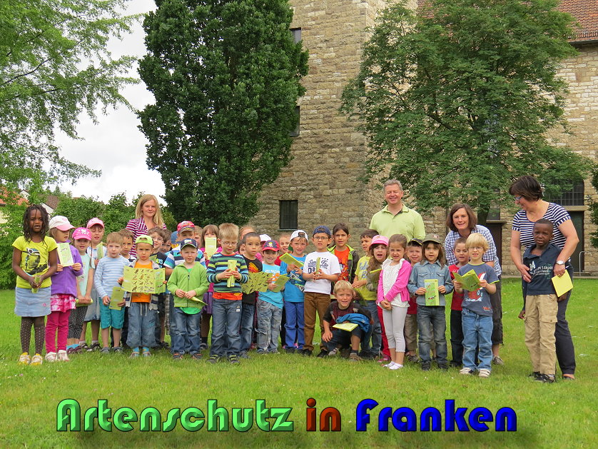 Eine Gruppe Kleinkinder steht lächelnd im Kirchgarten.